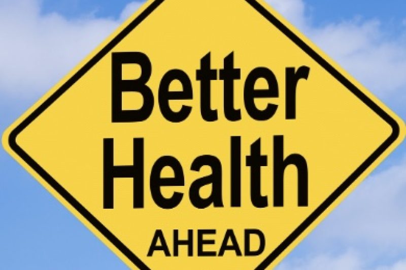 A yellow diamond shaped road sign with “Better Health AHEAD” in black block letters. Blue sky background with cumulus clouds. Overall a positively inspiring image.
