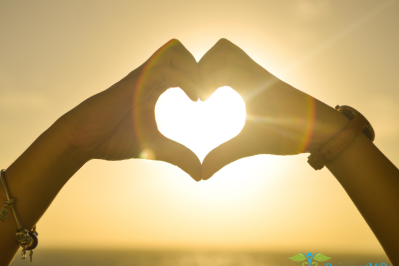 Sunset heart hands - a silhouette of someone making a heart shape with their hands against a beautiful sunset, symbolizing love and care in health and wellness, with the logo of Rejeune MD Wellness & Aesthetics at the bottom.